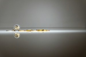a pair of gold coins sitting on top of a reflective surface
