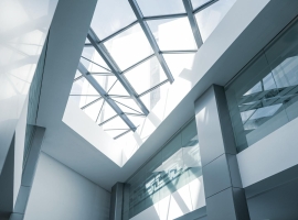An interior look at a modern office building featuring a glass ceiling and sleek steel frames.