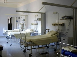 Spacious hospital room with several empty beds and medical equipment, emphasizing healthcare and hygiene.