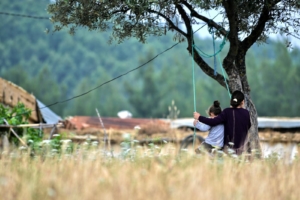 A serene moment of a mother and child on a swing under a tree in Oued Amlil, Morocco.