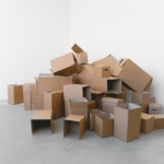 Launching a Recycled Paper Production Business in Nigeria A stack of various sized cardboard boxes in an empty room with a white background.