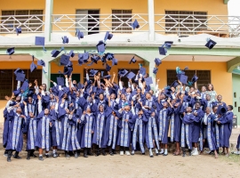 Group of graduates celebrating by tossing caps outside a building in Winneba, Ghana.