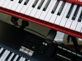 Vertical shot of red and black electronic keyboards in a home studio setting.