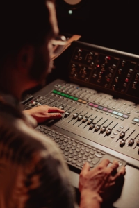 Audio engineer at work with mixing console in recording studio.