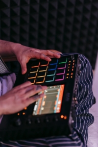 Musician using a colorful drum machine inside a soundproof studio, showing close-up details.