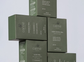 Close-up of stacked green boxes of skincare products by Canne featuring labels and benefits.