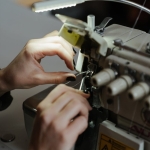 Launching and Apparel Production Business in Nigeria Hands adjusting a sewing machine, showcasing detailed needlework and craftsmanship.