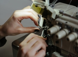 Hands adjusting a sewing machine, showcasing detailed needlework and craftsmanship.