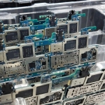 From above of circuit boards of modern smartphones placed in plastic box in electronics factory
