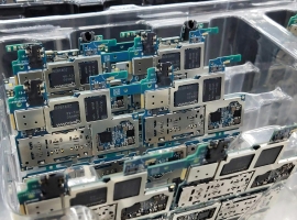 From above of circuit boards of modern smartphones placed in plastic box in electronics factory
