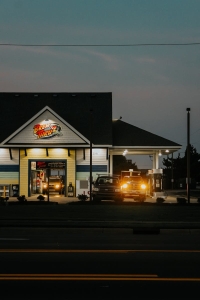 Illuminated drive-thru restaurant at night with cars lined up, showcasing a modern exterior.