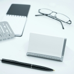 black framed eyeglasses beside white printer paper and black pen