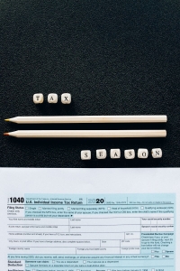 Creative composition featuring 1040 tax form, pencils, and letters spelling 'Tax Season' on black background.