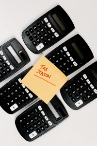Top view of black calculators arranged around 'Tax Season' sticky note, perfect for finance concepts.